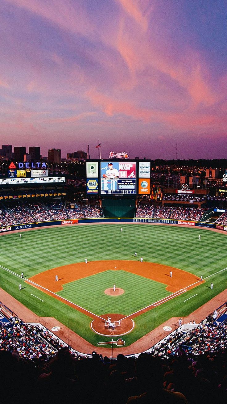 a baseball stadium filled with lots of people watching the game at sunset or sunrise time