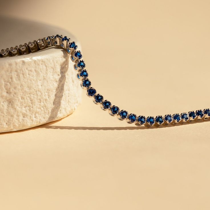 Make a shimmering statement with our Blue Sapphire Diamond Tennis Bracelet. Elegant and dainty, it adds the perfect bold, finishing touch to your outfit for special occasions like anniversaries or weddings. A minimalist accessory sure to shine and a dazzling symbol of “something blue” for brides. Material: High Quality Solid 925 Sterling Silver Finish: Sterling Silver ∙ 18K Gold Clasp: Box clasp and side prong closure Featuring a 6 inch (ONE SIZE) ~3mm Tennis Bracelet with half CZ Sapphire and h Timeless Blue Round Bracelets, Blue Diamond Cut Bracelet For Formal Occasions, Formal Sapphire Round Bracelets, Formal Round Sapphire Bracelet, Formal Blue Diamond-cut Bracelet, Formal Blue Diamond Cut Bracelet, Party Tennis Bracelet With Sparkling Stones, Blue Jewelry With Jubilee Bracelet For Anniversary, Sapphire Tennis Bracelet For Anniversary