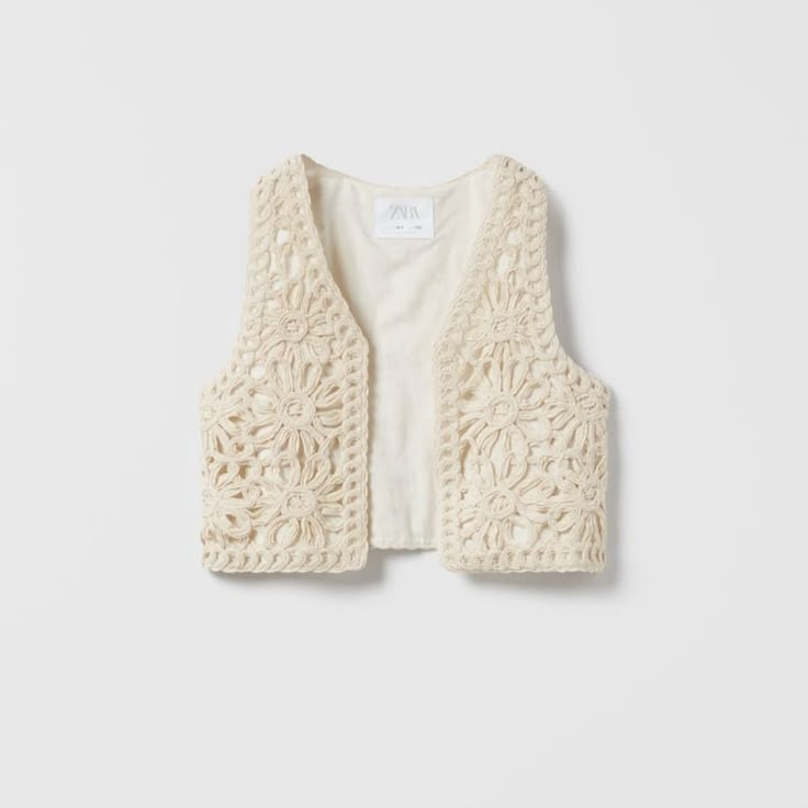 a white knitted vest with crochet details on the front and back, made from