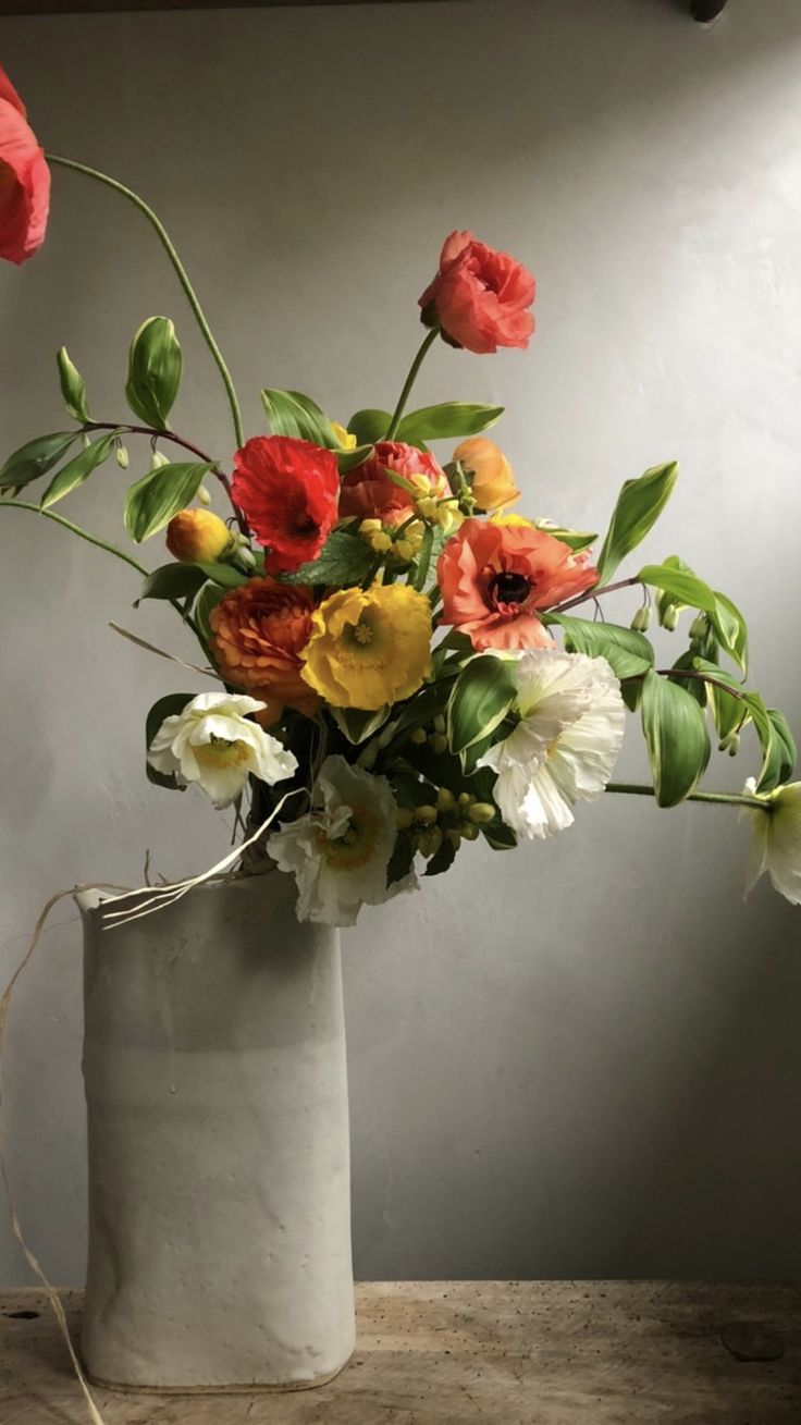 a white vase filled with lots of different colored flowers