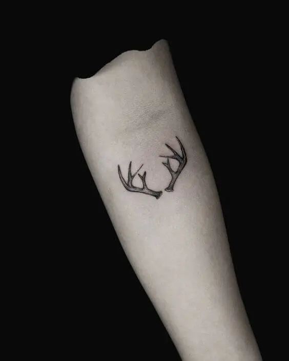 a small deer head tattoo on the arm