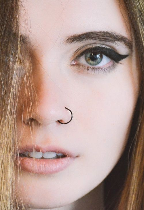 a close up of a woman's face with a nose ring