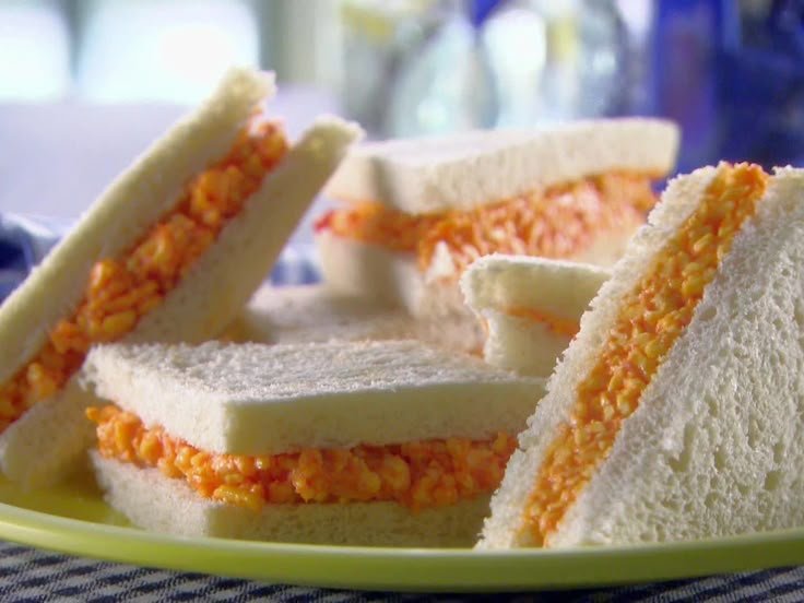 there are several sandwiches on the plate with orange and white frosting in between them