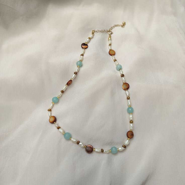 A summertime essential that adorns from day to night. This adjustable necklace was inspired by mesmerising summer days spent by the ocean. This is treasure is perfect for layering or to wear on its own. This necklace also looks stunning wrapped around the wrist as a bracelet. Reclaimed freshwater pearls, faceted aquamarine beads, brown mother of pearl beads, and yellow glass beads. Two available only in collar size (14") plus a 2" extension chain. Total length 16". 14ct gold filled clasp and fin Summer Ocean-inspired Necklaces, Adjustable Ocean-inspired Necklaces, Ocean-inspired Strand Necklaces For Jewelry Making, Ocean-inspired Necklaces For Summer Gifts, Bohemian Long Single Strand Pearl Necklace, Ocean-inspired Necklaces As Summer Gifts, Adjustable Ocean-inspired Strand Necklace, Ocean-inspired Adjustable Necklace As A Gift, Dainty Necklaces For Summer Beach