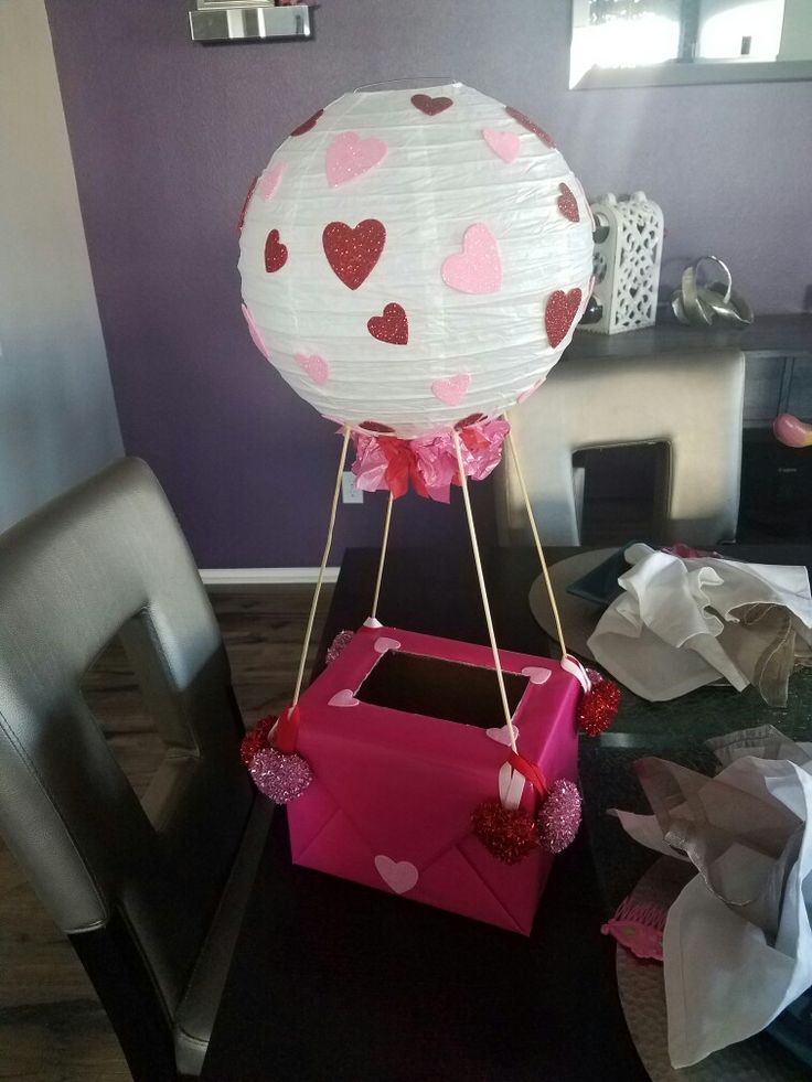 a hot air balloon sitting on top of a table next to a box with hearts