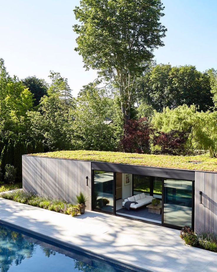 a house with a green roof next to a swimming pool