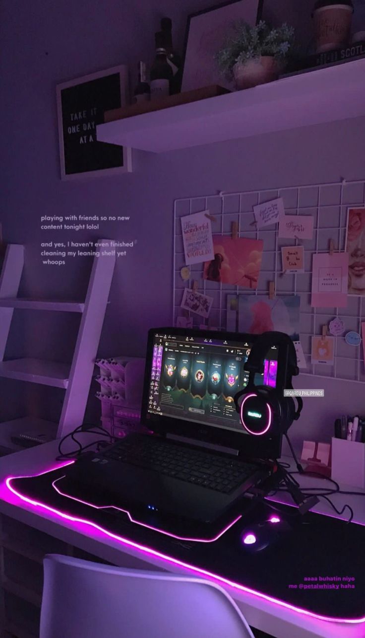 a laptop computer sitting on top of a desk under a purple light in a room