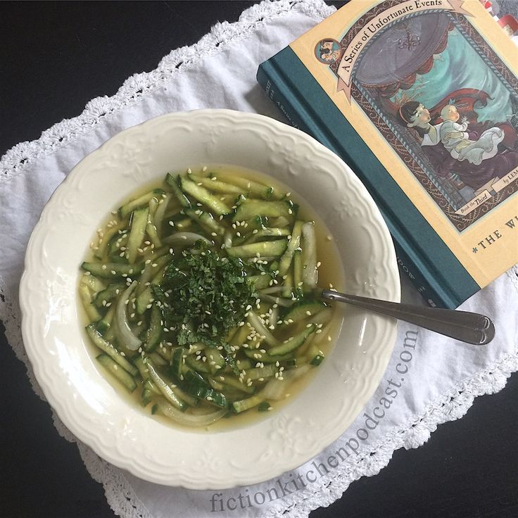 a white bowl filled with green beans and broth next to a book on a doily