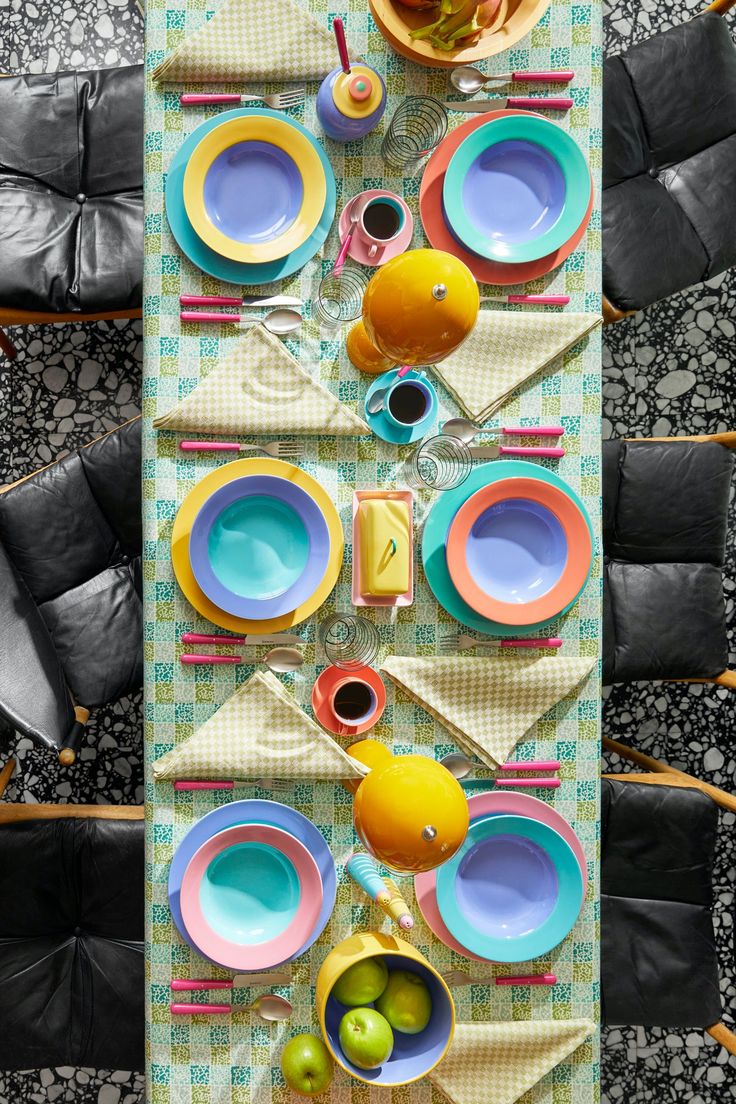 an overhead view of a table set with plates, bowls and fruit on it in the center