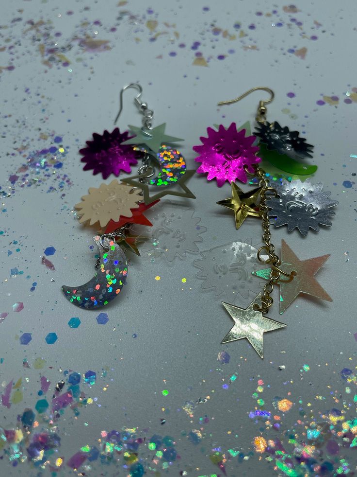 "Stargaze With These Celestial Sequin Earrings! In Gold & Silver!  ~Made from celestial sequin mix with gold or silver split rings, gold or silver drop chain and gold or silver fish hook earrings.  ~Celestial mix includes lil stars, medium stars, big stars, lil moons and suns with faces shapes in a variety of colors! ~All color of and placement of sequins are random and asymmetric :) ~Earrings measure 3\" inch in drop length roughly by about a 1/2\" inch in width roughly." Multicolor Star Charm Jewelry For Party, Multicolor Star-shaped Party Earrings, Multicolor Star Earrings For Parties, Whimsical Star-shaped Party Jewelry, Party Earrings With Star Charm, Party Earrings With Star Charm In Metal, Party Metal Earrings With Star Charm, Handmade Celestial Jewelry For Party, Star-shaped Metal Earrings For Party