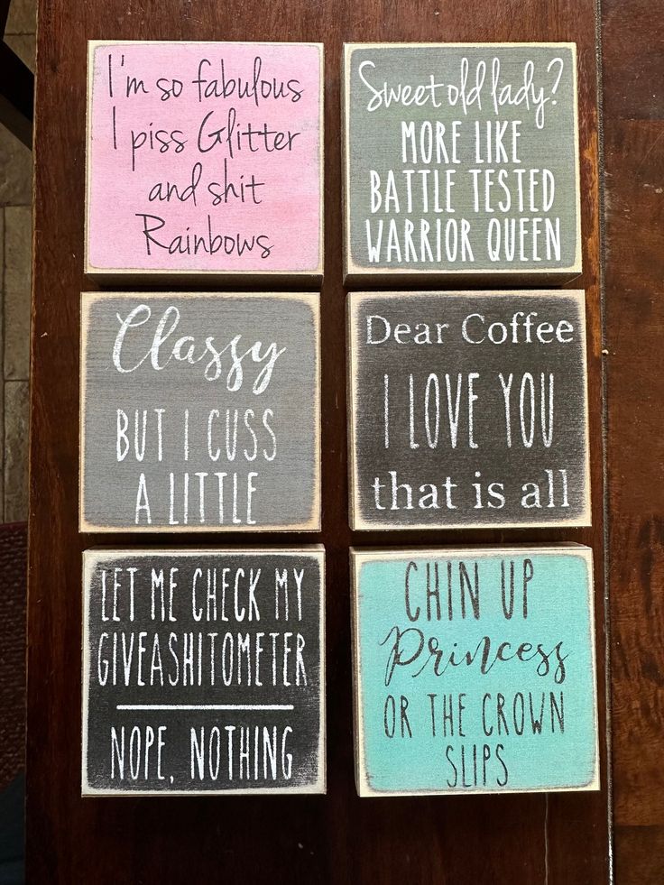 four coasters with different sayings on them sitting on a wooden table in front of a wall