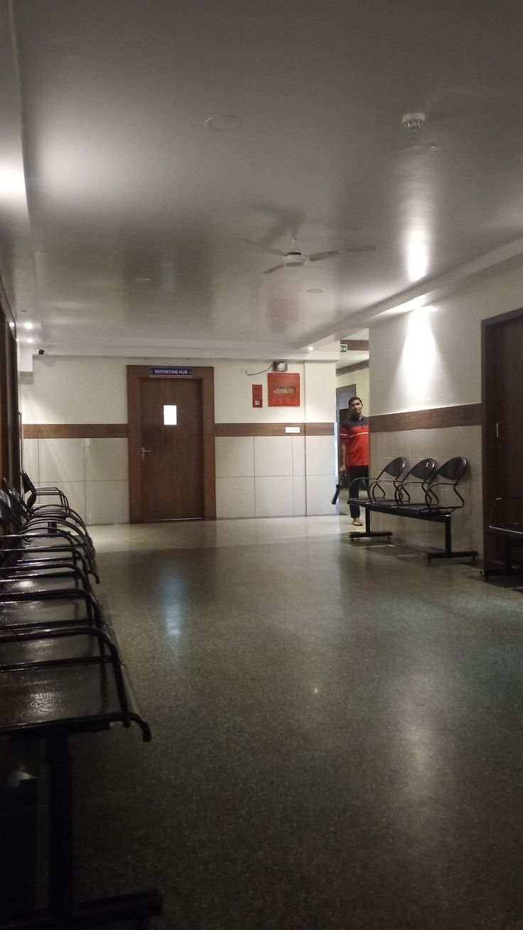 an empty room with benches and lights on the ceiling, in front of two doors