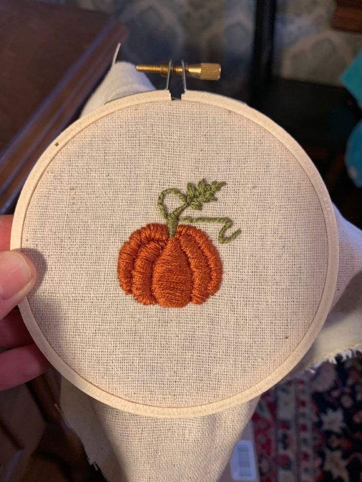 someone is holding up a small embroidered pumpkin