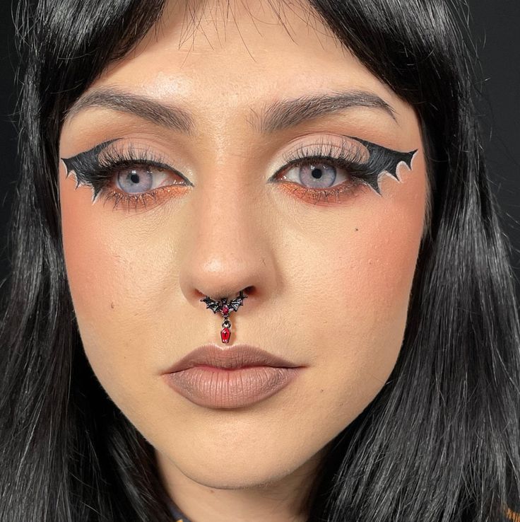 a close up of a woman with black hair and makeup on her face, wearing an elaborate nose piece