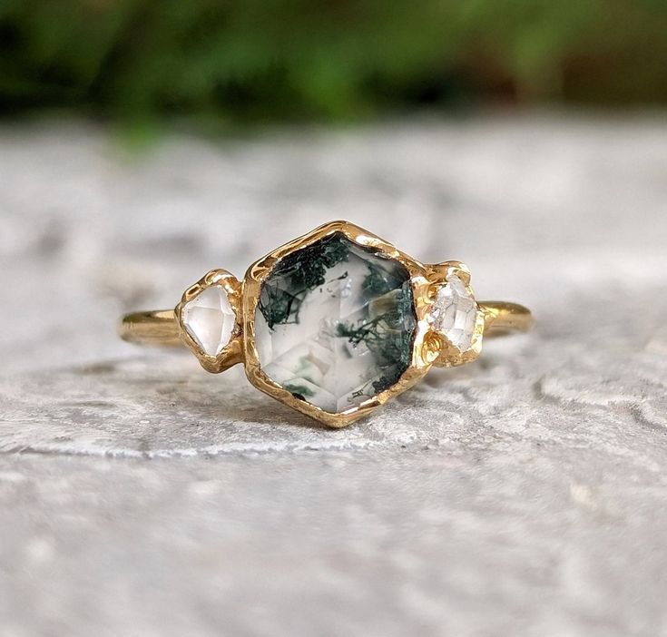 a close up of a ring on top of a stone surface with green plants in the background