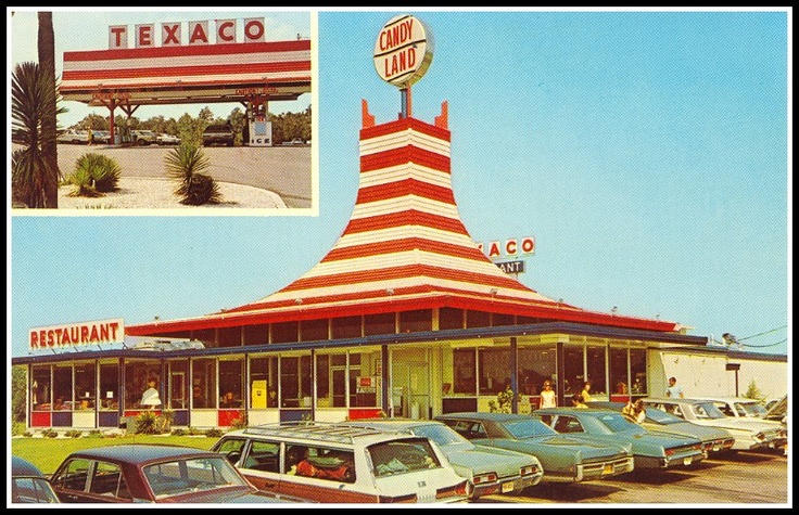 an old texaco gas station with cars parked in front and the sign above it