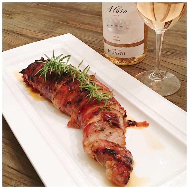 a white plate topped with meat and veggies next to a glass of wine