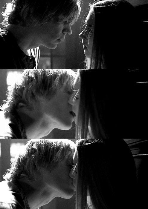 two people are kissing each other in black and white photo with light coming through the window