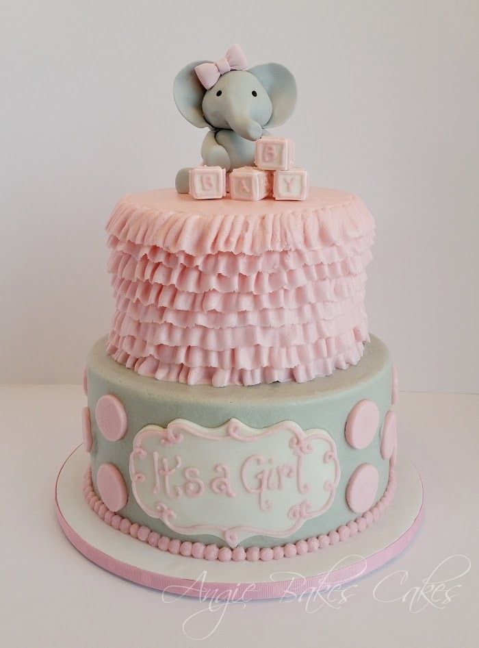 a pink and blue baby shower cake with an elephant topper on it's tier