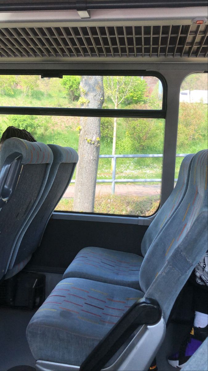 two seats in the back of a bus, one with an open window and another without