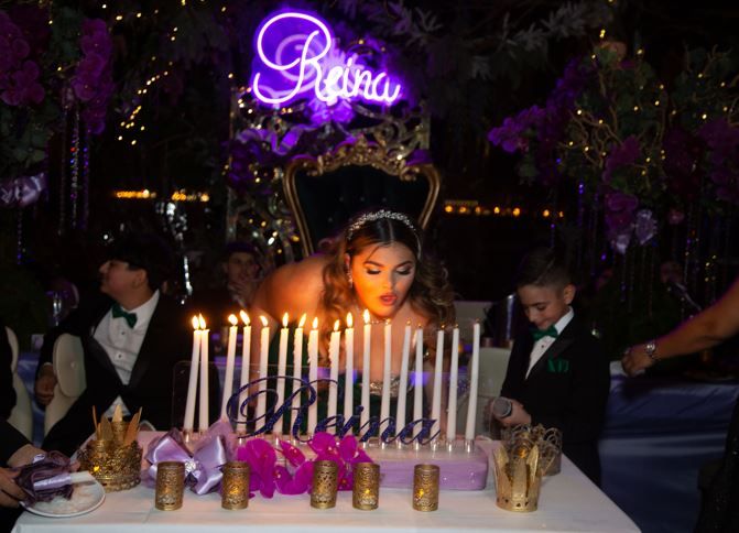 a woman sitting in front of a cake with candles