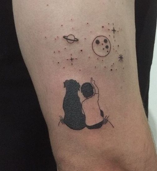 a person with a small tattoo on their arm that has an image of two people hugging