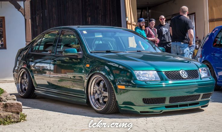 a green car parked in front of a group of people