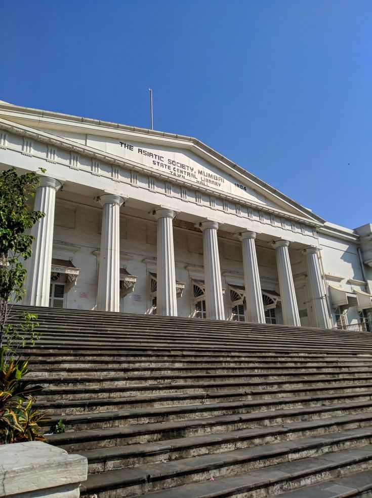 an old building with steps leading up to the front door and columns on each side