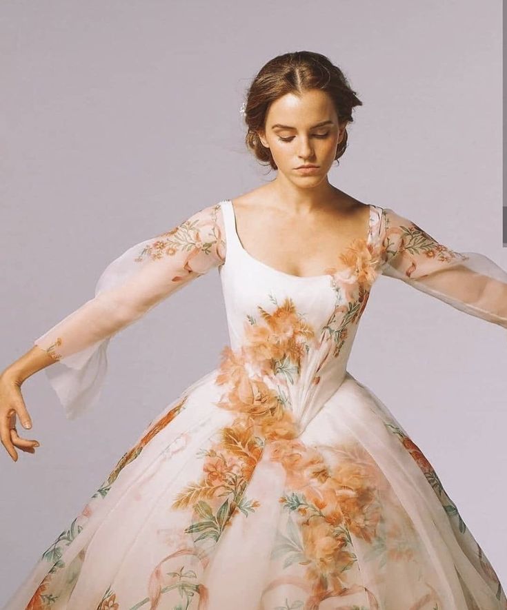 a woman in a white dress with orange flowers on it and her arms spread out