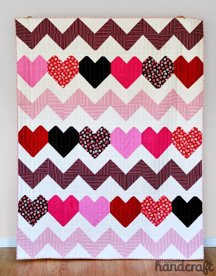 a quilted wall hanging with hearts on it