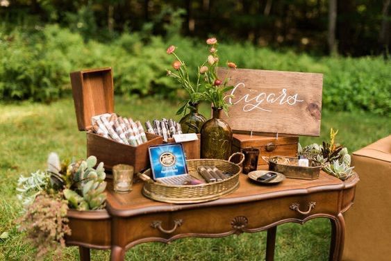 a wooden table topped with lots of different types of items next to a couch and chair