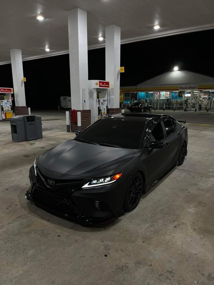 a black car is parked in an empty gas station