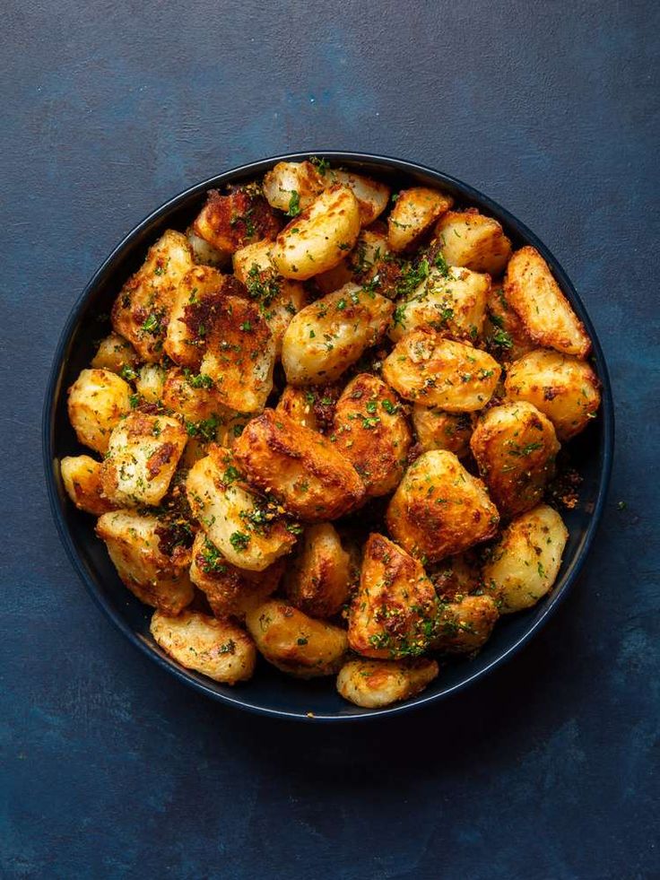 a black bowl filled with potatoes covered in seasoning