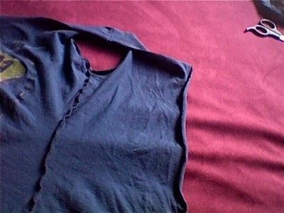 a blue shirt laying on top of a bed next to a pair of scissors and eyeglasses