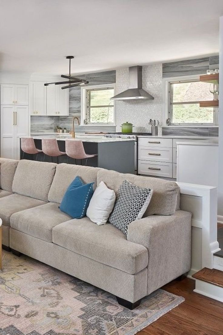 a living room filled with furniture next to a kitchen