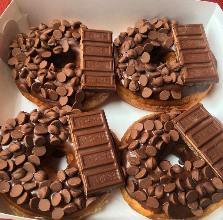 chocolate covered doughnuts in a box on top of each other with candy bars