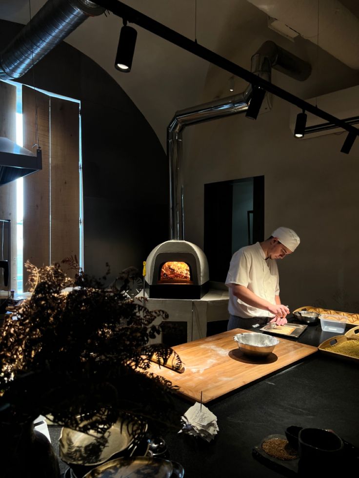 a chef is preparing food in an industrial style kitchen with wood burning oven and lighting