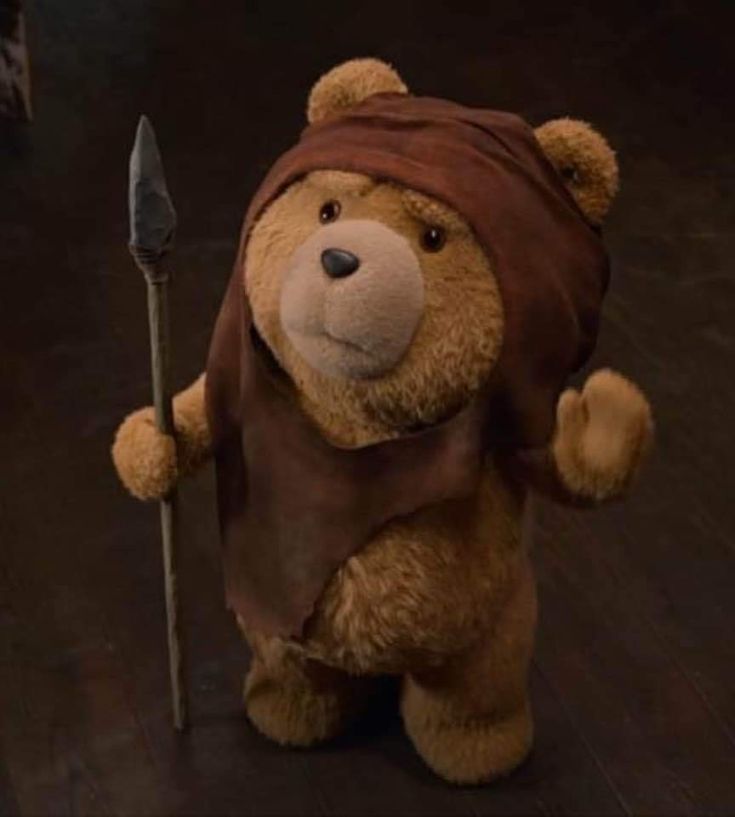 a brown teddy bear holding a spear on top of a wooden floor