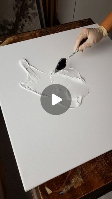 a person is using a brush to paint on a piece of white paper with black ink