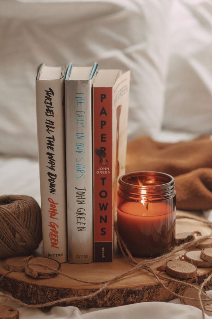 two books and a candle are sitting on a wood slice with twine between them