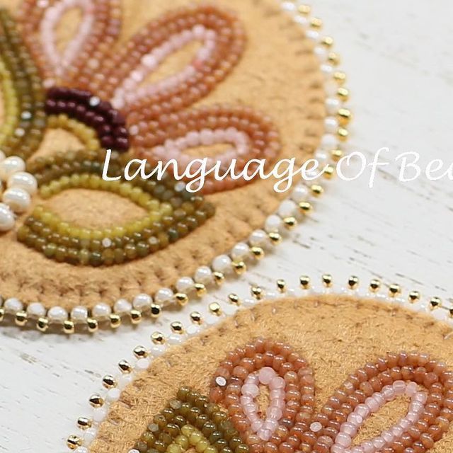 two beaded coasters sitting on top of a white wooden table next to each other