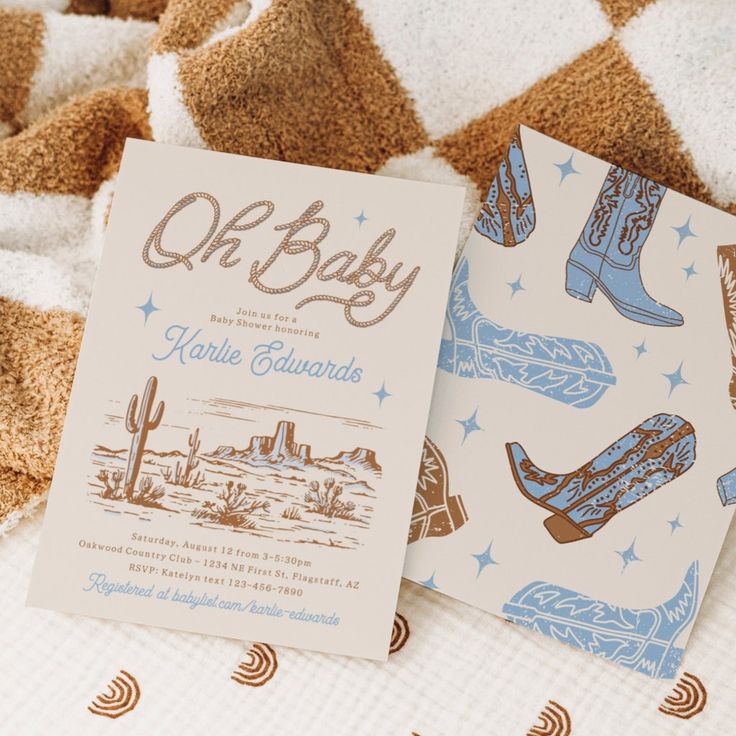 two baby cards sitting on top of a bed next to each other with cowboy boots