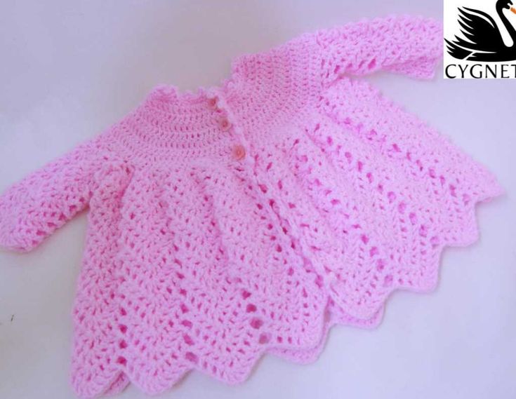 a pink crocheted sweater on a white surface