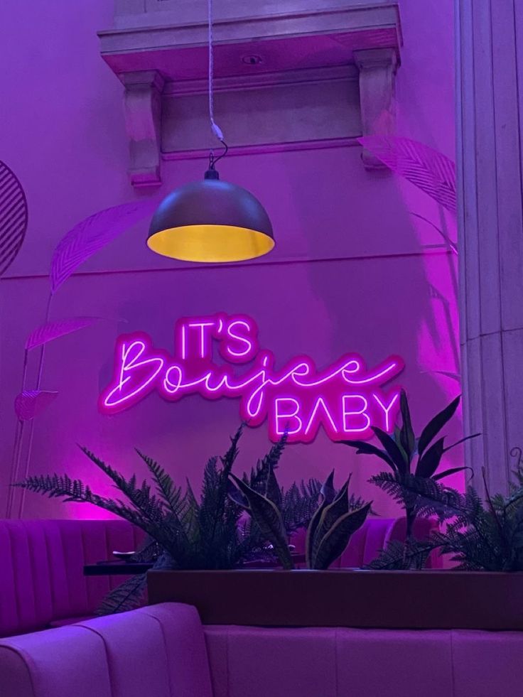 a neon sign that says it's a baby in front of a purple wall