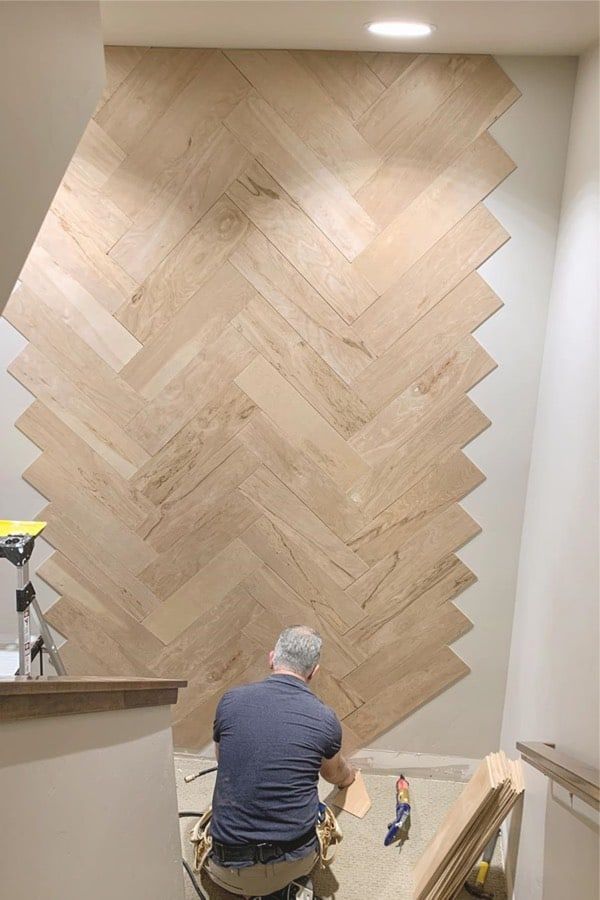 a man sitting on top of a wooden floor in front of a wood paneled wall