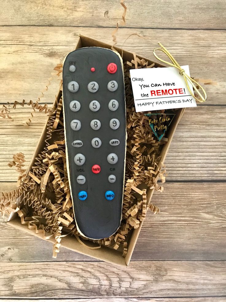 a remote control sitting in a box on top of wood shavings with a sign that says remote