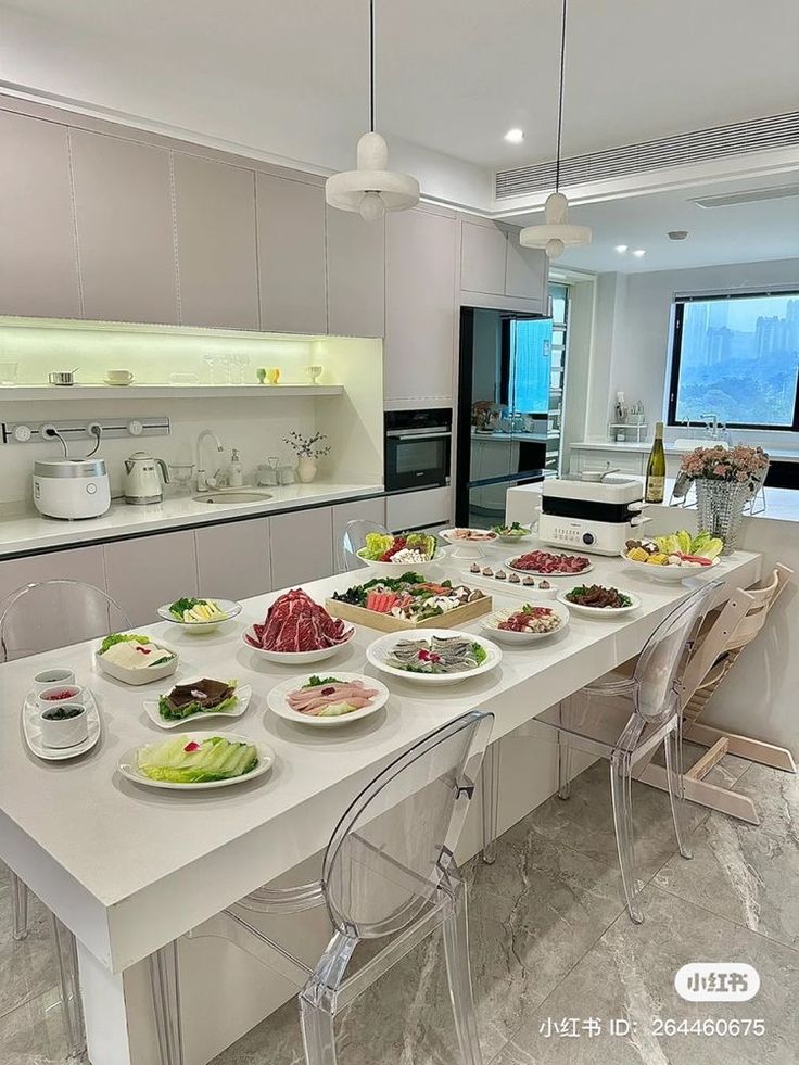 a long table with many plates of food on it in a large kitchen next to a window