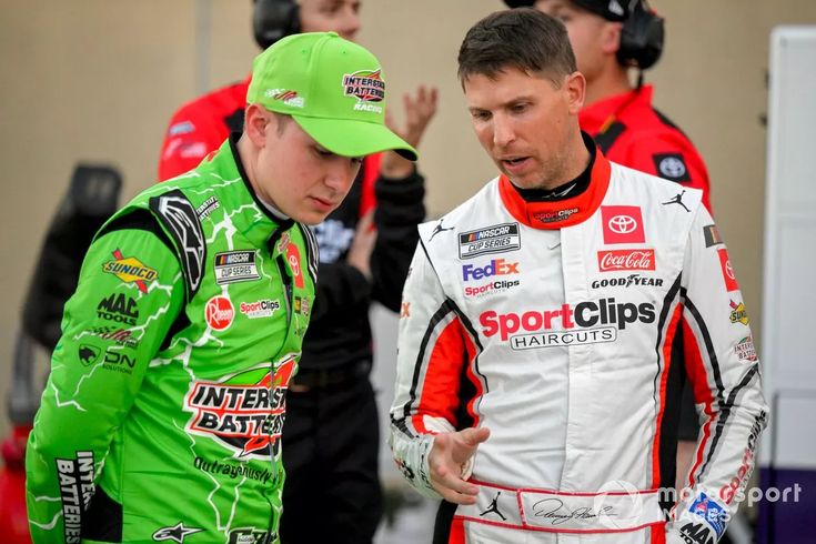 two men standing next to each other wearing green hats