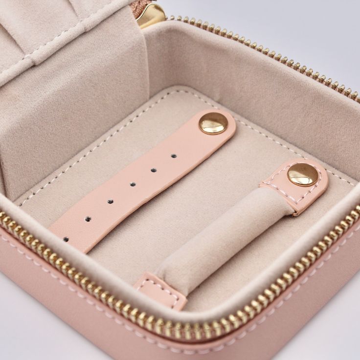 the inside of a pink case with gold hardwares and two watch straps in it