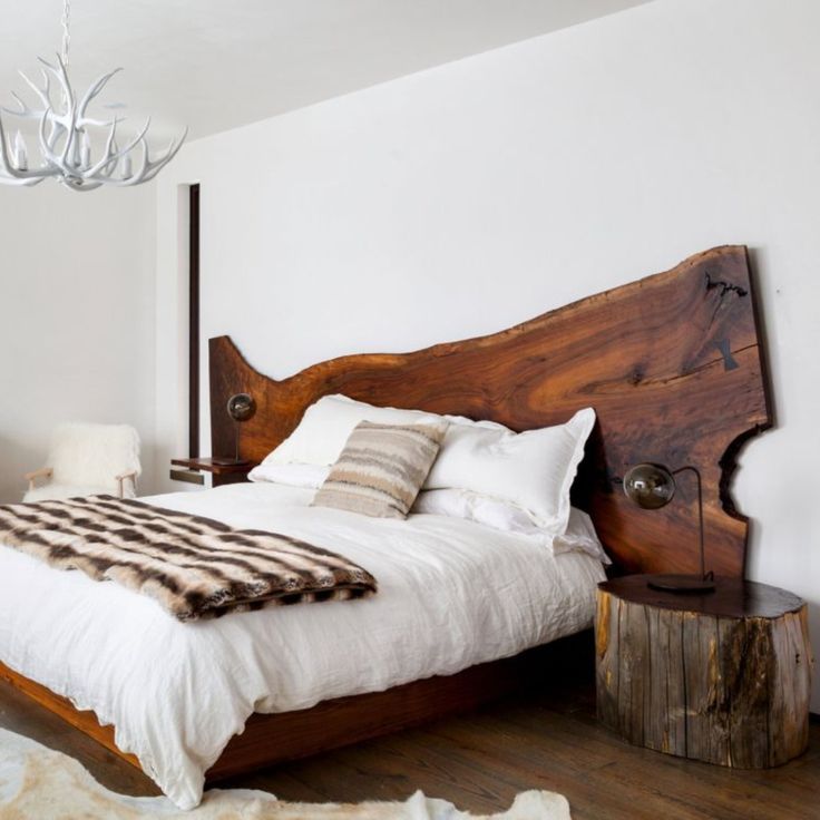 a bedroom with white walls and wooden furniture in the center, along with a chandelier hanging from the ceiling